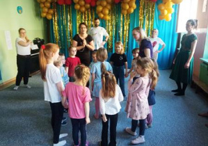 Dzieci stoją w małym kole, rodzice dookoła nich