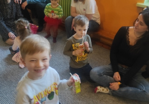 Rodzice wraz z dziećmi siedzą w kręgu i rozmawiają.