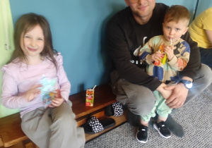 Tata z dziećmi siedzi na ławce.