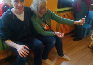 Rodzice siedzą na ławce i piją sok.