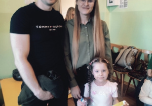 Rodzice z córką pozują do zdjęcia.