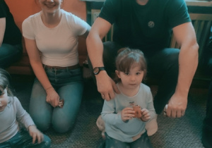 Rodzice pozują do zdjęcia z bliźniaczkami.