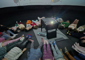 Dzieci leżą w namiocie i czekają na rozpoczęcie seansu