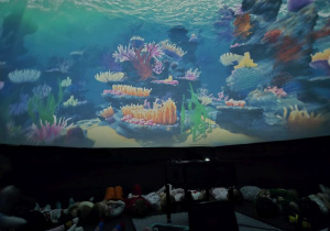 Dzieci leżą w namiocie i oglądają bajkę w Kinie Sferycznym