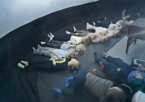 Dzieci leżą w namiocie i oglądają film