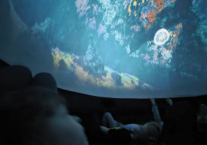 Dzieci leżą w namiocie i oglądają film