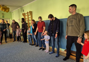 Rodzice i dzieci stoją i pokazują gesty