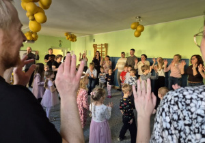 Rodzice i dzieci stoją i pokazują gesty