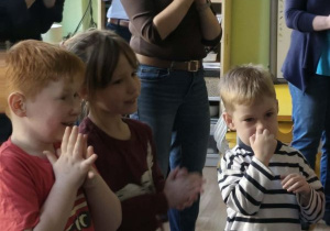 Rodzice i dzieci stoją i klaszczą