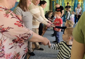 Rodzice i dzieci podczas zabaw integracyjnych podają sobie ręce