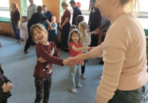 Rodzice i dzieci podczas zabaw integracyjnych podają sobie ręce