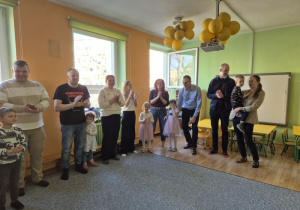 Dzieci stoją ze swoimi rodzicami