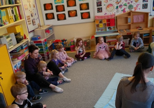 Dzieci siedzą w kręgu i obserwują środowisko wodne.