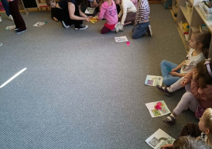 Dzieci otrzymują upominki (kolorowe rybki i opaski) od prowadzących warsztaty.