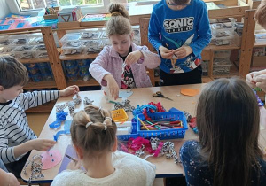 Dzieci wykonują pracę plastyczną przy stolikach