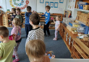 Dzieci na dywanie podczas zabawy ruchowej z wykonanymi z papieru i bibuły meduzami