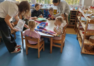 Dzieci wykonują pracę plastyczną przy stolikach
