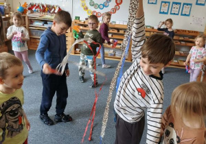 Dzieci na dywanie podczas zabawy ruchowej z wykonanymi z papieru i bibuły meduzami