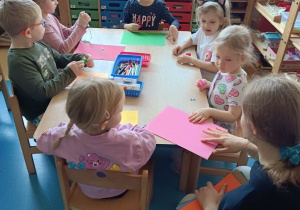 Dzieci wykonują pracę plastyczną przy stolikach