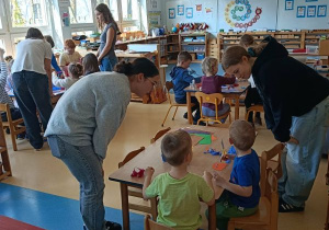 Dzieci wykonują pracę plastyczną przy stolikach