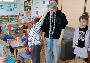 Chłopiec prezentuje wykonaną przez siebie meduzę, któr zasłania twarz prowadzącej zajecia