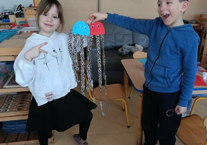 Chłopiec i dziewczynka prezentują wykonane przez siebie meduzy