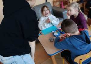 Dzieci wykonują pracę plastyczną przy stolikach