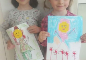 Dziewczynki prezentują prace plastyczne przedstawiające postacie Lego