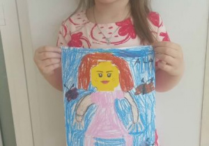 Dziewczynka prezentuje narysowaną postać z Lego