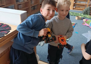 Chłopcy pozują do zdjęcia trzymając w dłoniach samochody zbudowane z klocków Lego