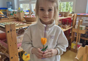 Dziewczynka pozuje do zdjęcia z kwiatkiem z klocków Lego