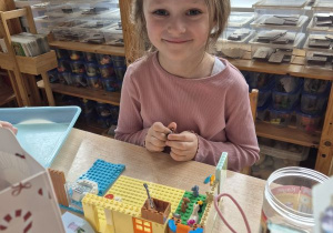Dziewczynka bawi się przy stoliku klockami Lego