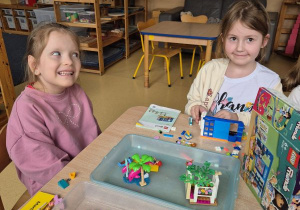 Dziewczynki bawią się przy stoliku klockami Lego