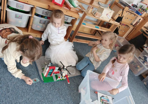 Dziewczynki siedzą na dywanie i układają szpital z klocków Lego
