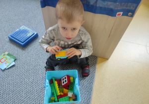 Chłopiec pokazuje samochodzik z klocków DUPLO.