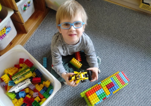 Chłopiec prezentuje koparkę z klocków LEGO.