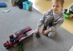 Chłopiec pokazuje samochód ciężarowy zbudowany z klocków LEGO.