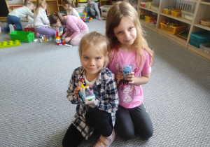 Dziewczynki prezentują swoje budowle z klocków LEGO.