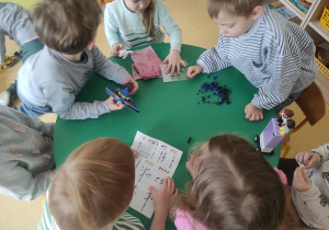 Dzieci budują z klocków LEGO według instrukcji.