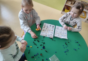 Dziewczynki budują z klocków LEGO według instrukcji.