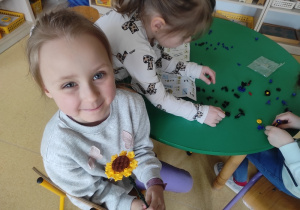 Dziewczynka prezentuje kwiatka z klocków LEGO.