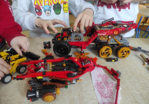Chłopcu budują pojazdy z klocków LEGO.