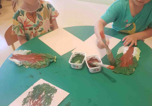 Dziewczynka maluje farbą liść kapusty