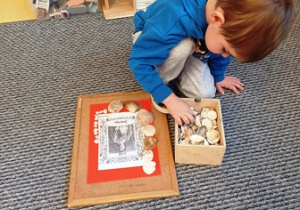 Szymon układa ramkę z muszli wokół zdjęcia sławnej kobiety