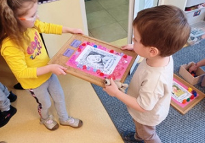 Marysia i Kazik przenoszą podkładkę ze swoją pracą