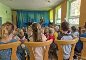 Dzieci siedzą na widowni i słuchają koncertu muzycznego
