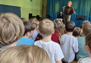 Dzieci siedzą na widowni i słuchają koncertu muzycznego