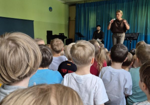 Dzieci siedzą na widowni i słuchają koncertu muzycznego