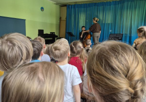 Dzieci siedzą na widowni i słuchają koncertu muzycznego