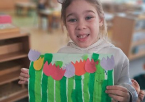 Dziewczynka prezentuje swoją pracę plastyczną przedstawiającą tulipany